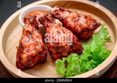 BBQ Hähnchenflügel mit würziger Sauce auf einem Holzteller Stockfoto