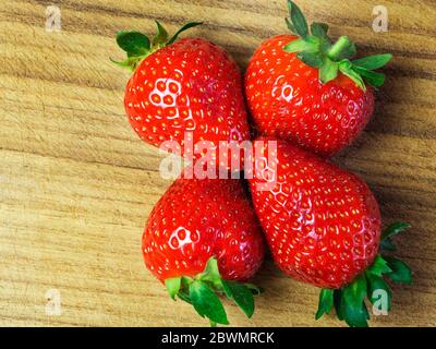 Vier Erdbeeren auf einem Holzhackbrett Stockfoto