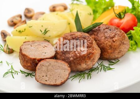 Hausgemachte Koteletts mit Kartoffeln und Gemüse auf weißem Hintergrund. Stockfoto