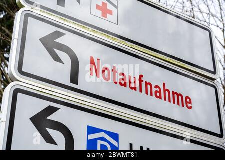 Richtungsschild zeigt das Rote Kreuz und deutschen Text Notaufnahme, was bedeutet, Notaufnahme, an der Zufahrt zu einem großen Krankenhaus Stockfoto