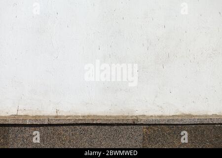 Weiße Wand mit rotem Granitsockel. Stockfoto