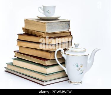 Ein Stapel alter Bücher und ein elegantes Kaffeeset. Auf weißem Hintergrund. Stockfoto