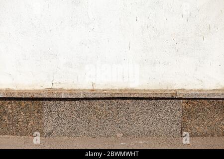 Weiße Wand mit rotem Granitsockel. Stockfoto