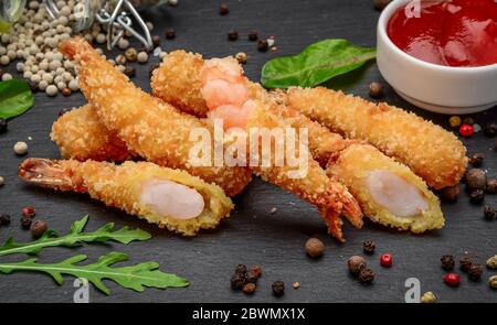 Gebratene Shrimps Tempura mit süßer Chilisauce auf einem schwarzen Steinbrett Stockfoto