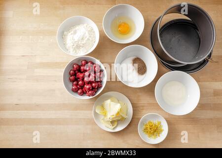 Zutaten in weißen Schalen zum Backen eines Kirschkuchen in einer Springform Pfanne auf einer hölzernen Küchenarbeitsplatten, Kopierraum, hohe Winkelansicht von oben, ausgewählt Stockfoto