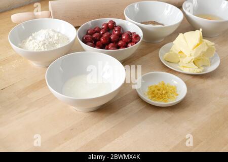 Backen zu Hause, Zutaten in weißen Schalen für einen Kirschkuchen auf einer hölzernen Küchenarbeitspfläche, Kopierfläche, ausgewählter Fokus, schmale Schärfentiefe Stockfoto