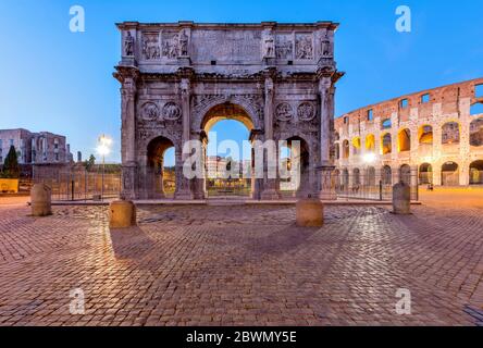 Konstantinsbogen - Blick in die Dämmerung auf die Südseite des Konstantinsbogens, zwischen dem Kolosseum, rechts, und dem Forum Romanum, links. Rom, Italien. Stockfoto