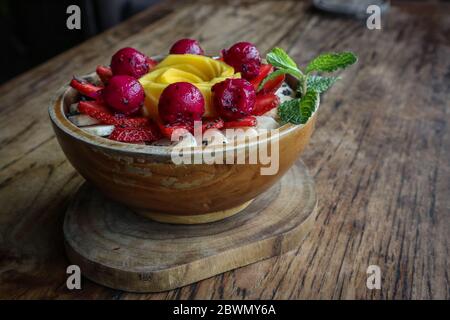 Smoothie Schüssel mit Mango, Erdbeere, Banane und Drachenfrucht in Holzschüssel auf Holzhintergrund dekoriert. Konzept der gesunden Frühstück Stockfoto