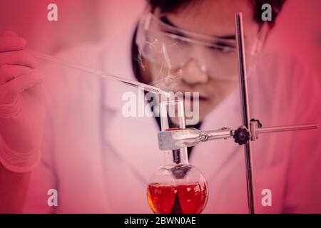 Junge asiatische Wissenschaftler sorgfältig Tests der schrecklichen Gefahr und Risiko chemische Formel oder Virus in Science Lab Konzept. Stockfoto