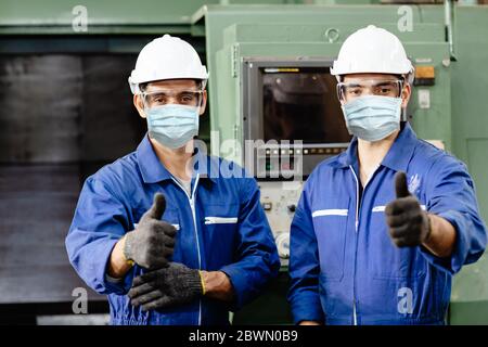 Arbeiter tragen Gesichtsschutz oder Einweg-Gesichtsmaske während der Arbeit Service in der Fabrik Coronavirus (Covid-19) oder Luftverschmutzung Verschmutzung in der Fabrik zu verhindern Stockfoto