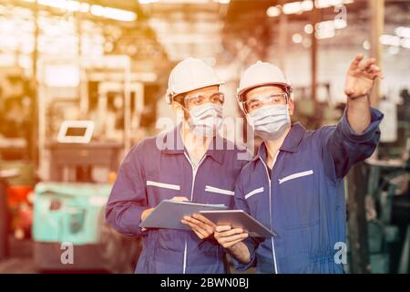 Ingenieur Teamwork Arbeiter tragen Einweg-Gesichtsmaske oder Gesichtsschutz während der Arbeit in der Fabrik zu Covid-19 Virus Luftverschmutzung und für go zu verhindern Stockfoto