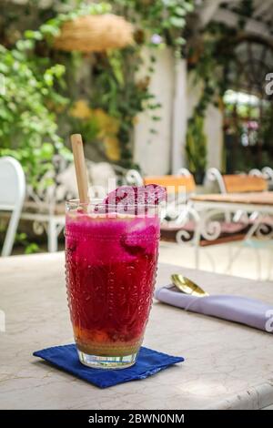 Rosa Saft mit Äpfeln, Rote Bete, Drachenfrucht und Limette im Glas mit Bambus Trinkhalm auf dem Tisch im Café Stockfoto