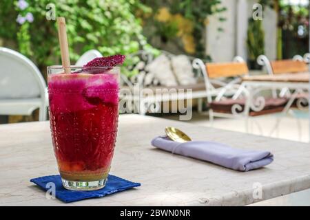 Rosa Saft mit Äpfeln, Rote Bete, Drachenfrucht und Limette im Glas mit Bambus Trinkhalm auf dem Tisch im Café Stockfoto