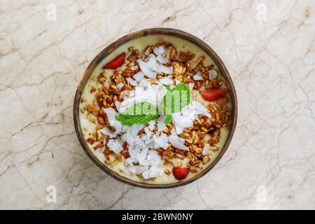 Smoothie Schüssel mit Mango, Joghurt, Müsli und Erdbeere in Kokosnussschale Schüssel auf hellem Hintergrund, Draufsicht Stockfoto