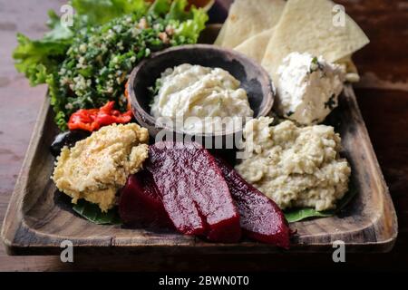 Mezze-Platte mit Hummus, Babaganoush, Tabouli, gerösteten Paprika, Rüben, Feta-Käse und kalamata-Oliven serviert mit Pita-Brot Stockfoto