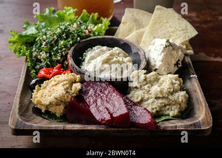 Mezze-Platte mit Hummus, Babaganoush, Tabouli, gerösteten Paprika, Rüben, Feta-Käse und kalamata-Oliven serviert mit Pita-Brot Stockfoto