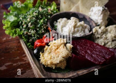 Mezze-Platte mit Hummus, Babaganoush, Tabouli, gerösteten Paprika, Rüben, Feta-Käse und kalamata-Oliven serviert mit Pita-Brot Stockfoto