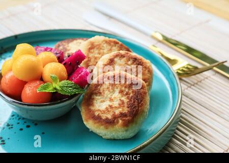 Vegane Tofu-Käse-Pfannkuchen auf blauem Teller mit frischen tropischen Früchten und Kokosnusscreme Stockfoto