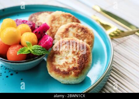 Vegane Tofu-Käse-Pfannkuchen auf blauem Teller mit frischen tropischen Früchten und Kokosnusscreme Stockfoto