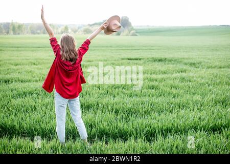 Stilvolle Frau genießen Frühling und Natur auf dem grünen Feld, Rückansicht. Konzept eines unbeschwerten Lebensstils und Freiheit Stockfoto