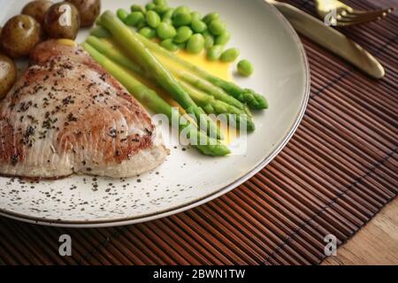 Gegrilltes Thunfischsteak mit Spargel, gebratenen Babykartoffeln, Edamamebohnen und Sauce Hollandaise auf einem Teller, Draufsicht Stockfoto