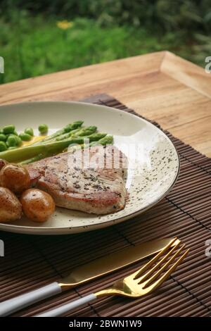 Gegrilltes Thunfischsteak mit Spargel, gebratenen Babykartoffeln, Edamamebohnen und Sauce Hollandaise auf einem Teller, Draufsicht Stockfoto