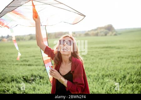 Porträt einer jungen und unbeschwerten Frau, die den Drachen auf dem Grünfeld startet. Konzept des aktiven Lebensstils in der Natur Stockfoto