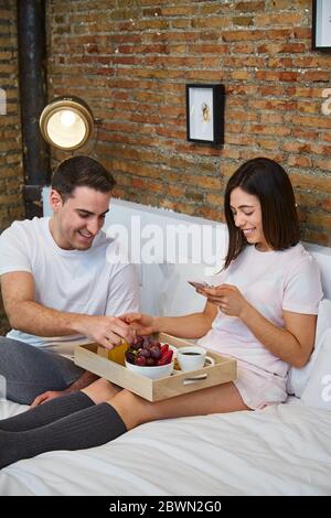 Junges Paar mit einem gesunden Frühstück und Entspannung im Bett im Haus. Stockfoto