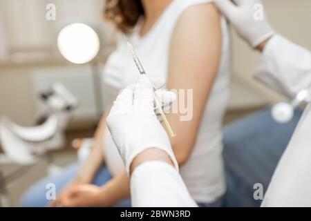 Arzt hält Impfstoff oder einige Medikamente in der Spritze, Vorbereitung für die Injektion für eine schwangere Frau während eines medizinischen Verfahrens in der Klinik, Nahaufnahme Stockfoto