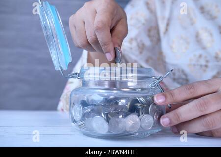 Nahaufnahme von Frauen Hand speichern Münzen im Glas. Stockfoto