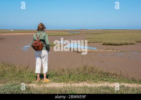 Norfolk Küstenweg, Rückansicht einer Wanderin, die auf dem North Norfolk Küstenweg in der Nähe von Blakeney steht und das Naturschutzgebiet Salzmarschen, Großbritannien, betrachtet Stockfoto