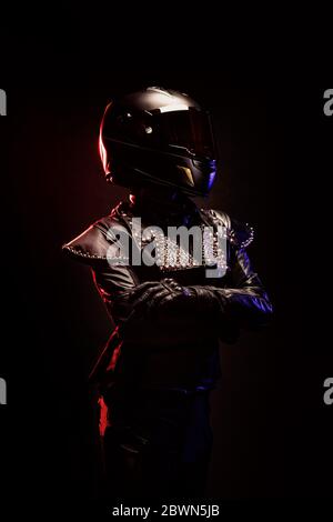 Porträt einer jungen Biker-Frau mit einer Nieten Lederjacke und einem schwarzen Helm Stockfoto