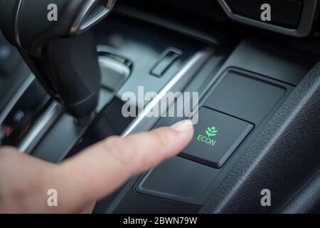 Drücken Sie die Taste econ im Armaturenbrett des Autos mit den Fingern. Reduzierung des Kraftstoffverbrauchs Stockfoto