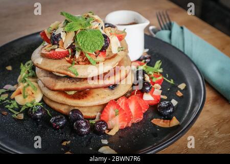 Pfannkuchen mit Banane, Heidelbeeren, Erdbeeren und Schokoladensauce auf einem Teller Nahaufnahme Stockfoto