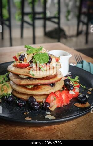 Pfannkuchen mit Banane, Heidelbeeren, Erdbeeren und Schokoladensauce auf einem Teller Nahaufnahme Stockfoto