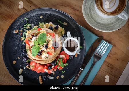 Pfannkuchen mit Banane, Heidelbeeren, Erdbeeren und Schokoladensauce auf einem Teller Draufsicht Stockfoto