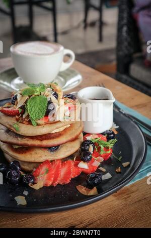 Pfannkuchen mit Banane, Heidelbeeren, Erdbeeren und Schokoladensauce auf einem Teller Nahaufnahme Stockfoto