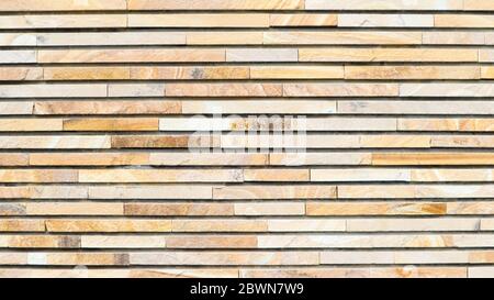Dekorative Textur einer schönen Wand mit rechteckigen Teilen aus mehrfarbigen Kunststein. Collage aus schmalen Granitblöcken. Außenfinis Stockfoto