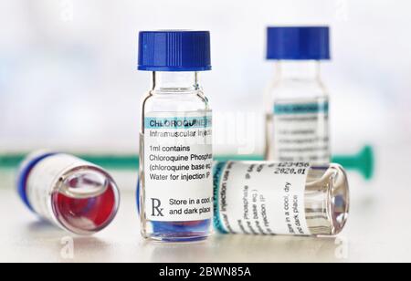 Chloroquinphosphat (generischer Name) Medikament in kleinen Injektionsflaschen mit blauen Kappen, verschwommener Spritzenhintergrund (eigenes Label-Design mit Dummy-Daten - nein Stockfoto