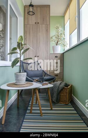 Interieur des gemütlichen Balkon mit grünen Wänden, Sitzecke mit Teppich, Sessel und zwei Couchtische Stockfoto