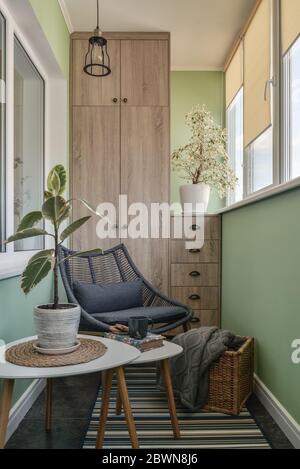 Interieur des gemütlichen Balkon mit grünen Wänden, Sitzecke mit Teppich, Sessel und zwei Couchtische Stockfoto