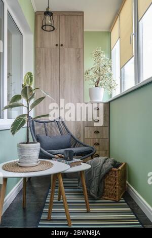 Interieur des gemütlichen Balkon mit grünen Wänden, Sitzecke mit Teppich, Sessel und zwei Couchtische Stockfoto