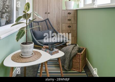 Interieur des gemütlichen Balkon mit grünen Wänden, Sitzecke mit Teppich, Sessel und zwei Couchtische Stockfoto