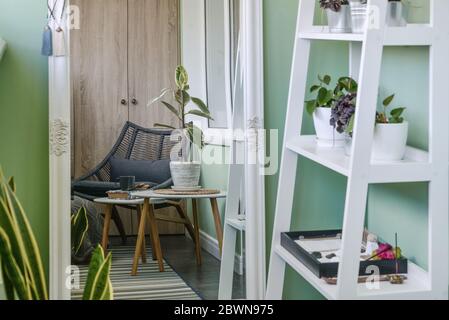 Interieur des gemütlichen Balkon mit grünen Wänden, Sitzecke mit Teppich, Sessel und zwei Couchtische Stockfoto