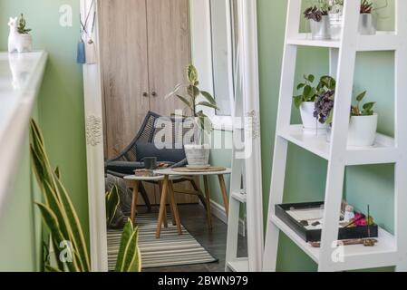 Interieur des gemütlichen Balkon mit grünen Wänden, Sitzecke mit Teppich, Sessel und zwei Couchtische Stockfoto