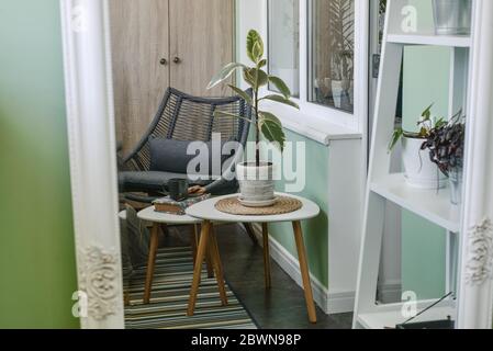 Interieur des gemütlichen Balkon mit grünen Wänden, Sitzecke mit Teppich, Sessel und zwei Couchtische Stockfoto