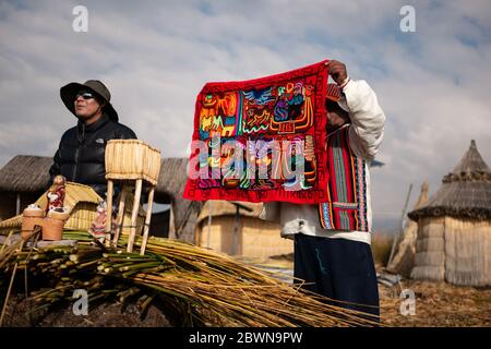 Die Uros-Gemeinschaft zeigt ihr Handwerk, während Touristen ihre schwimmende Insel aus Totorareed am Titicaca-See in Peru besuchen. Stockfoto