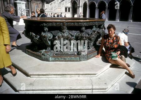 Frau sitzt am Brunnen aus Bronze Brunnen-Köpfe von Bildhauer Alfonso Alberghetti im Hof des Dogenpalastes, Venedig, Italien im Bild im Jahr 1964 Stockfoto