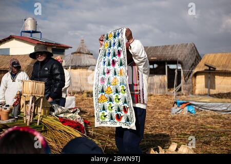 Die Uros-Gemeinschaft zeigt ihr Handwerk, während Touristen ihre schwimmende Insel aus Totorareed am Titicaca-See in Peru besuchen. Stockfoto