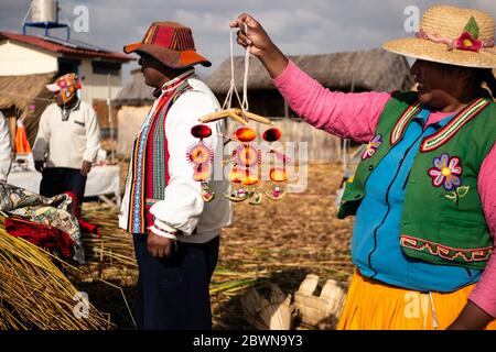 Die Uros-Gemeinschaft zeigt ihr Handwerk, während Touristen ihre schwimmende Insel aus Totorareed am Titicaca-See in Peru besuchen. Stockfoto